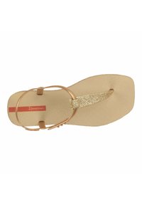 Infradito beige con soletta testurizzata, cinturino glitterato oro e lacci rotondi per le dita. Presenta un piccolo logo rosso sulla suola.