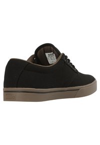 Black canvas sneakers with a low-top design, featuring lace-up closure, a brown inner lining, and a textured rubber sole.