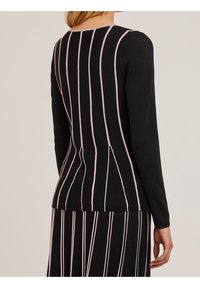 Musta pitkähihaisuus paita, jossa on vaaleanpunaiset pystyrivit, ymp round-kaula-aukko ja istuva muotoilu. Pehmeä rakenne, muotoiltu siluetti.