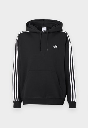 Μαύρη φούτερ μπλούζα με κουκούλα, φτιαγμένη από βαμβάκι, με μπροστινή τσέπη, λευκή τριάδα γραμμών σχεδιασμού στα μανίκια και μικρό λευκό λογότυπο στο στήθος.