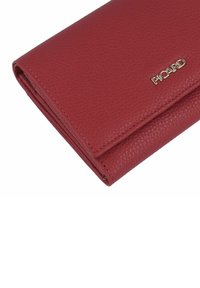 Portefeuille en cuir rouge avec une finition texturée, au design plié, et accent logo doré. Présente un profil mince et des coutures soignées.
