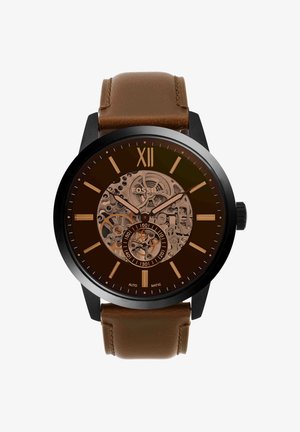 Montre ronde noire Fossil avec bracelet en cuir marron, cadran squelette montrant les engrenages, chiffre romain XII et index ainsi que aiguilles dorés.