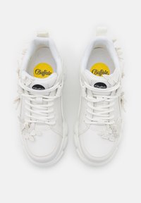 Baskets de la marque White Buffalo avec semelles épaisses, lacets à l'avant et accents décoratifs de papillons blancs sur un fond propre.