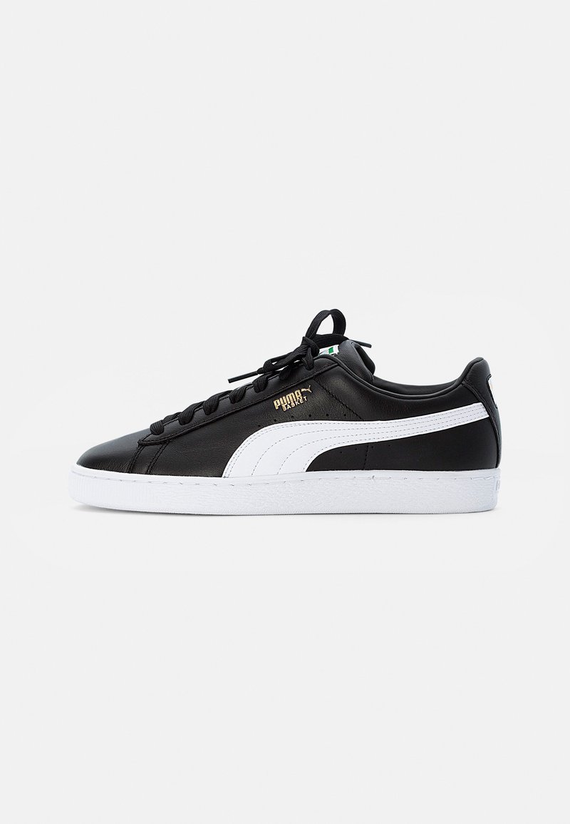 Fekete bőr sneaker fehér kiegészítőkkel, lekerekített orral, lapos fűzőkkel és textúrázott talppal. Arany logó részlet az oldalon.