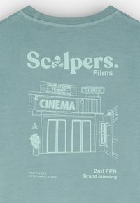 T-shirt bleu clair avec une image blanche d'une façade de cinéma, accompagnée du texte : "Scalpers Films", les horaires des séances et un symbole de crâne.