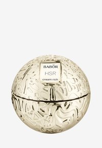 Guldfärgad sfärisk burk med texturerad yta och präglad design. Etiketten säger "BABOR HSR cream rich." Sömnad synlig runt mitten.