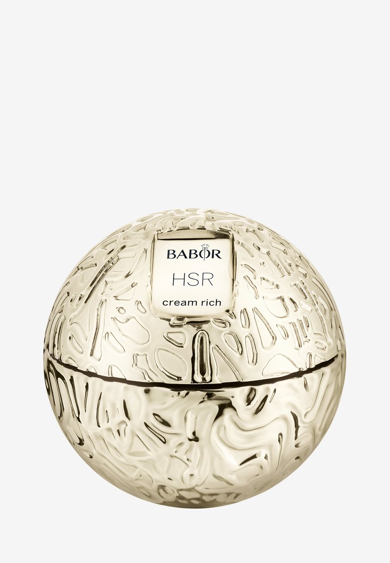Guldfärgad sfärisk burk med texturerad yta och präglad design. Etiketten säger "BABOR HSR cream rich." Sömnad synlig runt mitten.