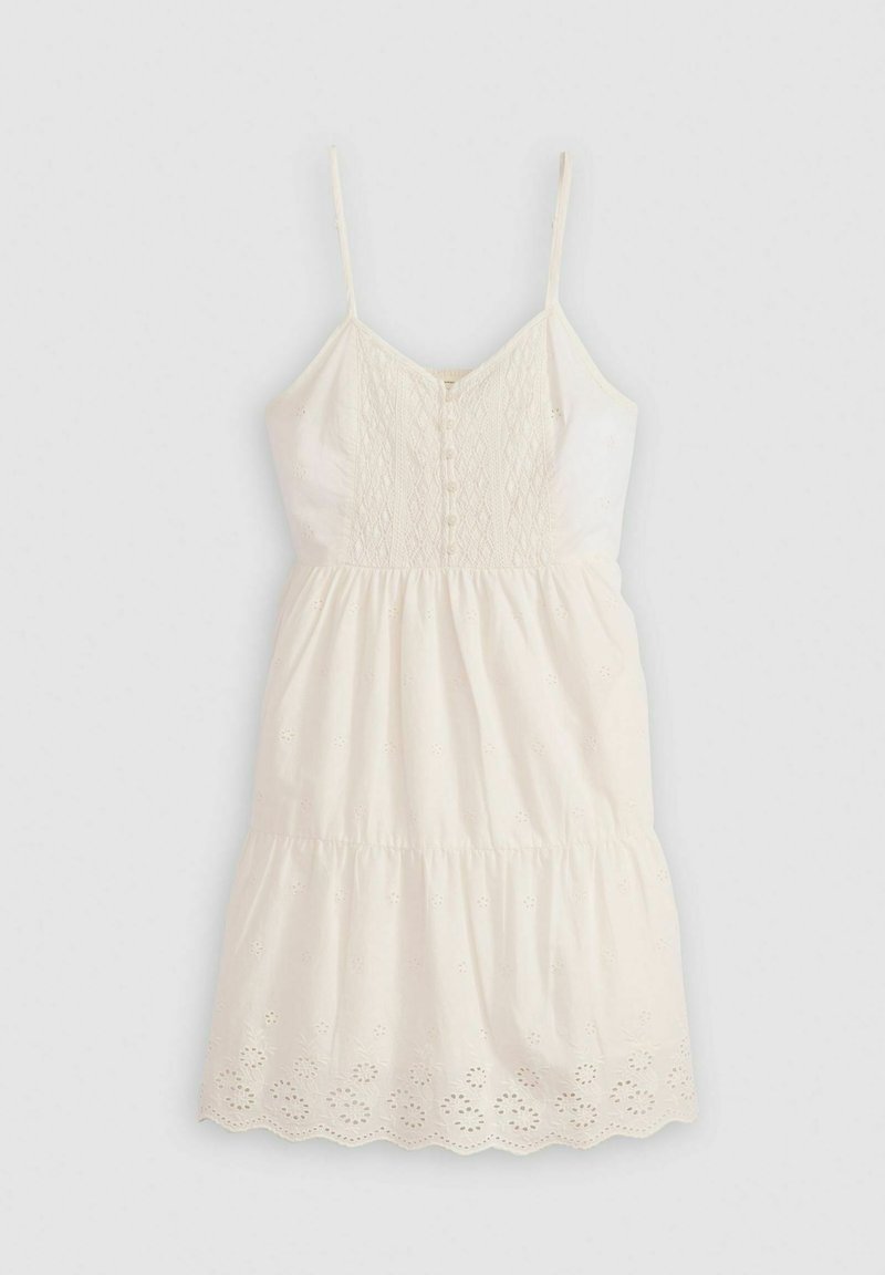 Vestido de algodón blanco con un corsé ajustado, tirantes de espagueti ajustables, detalles bordados y una falda acampanada en capas con un dobladillo en forma de ondas.