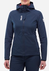 Veste de sport bleu marine en tissu léger, avec une capuche, une fermeture éclair intégrale et des accents de logo sur la poitrine et la manche.