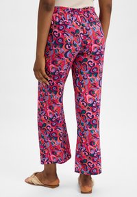 Colorful patterned pants with a relaxed fit, featuring a vibrant swirl design in pink, purple, and green, an elastic waistband, and flat hems.