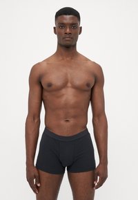 Boxeri scurți din bumbac negru cu o talie elastică moale. Proiectați cu o formă ajustată, textură netedă și cusături minime pentru confort.