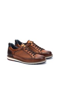 Zapatillas de cuero marrón con paneles laterales texturizados, puntera redonda y suela blanca en contraste. Presenta cordones oscuros y detalle de marca en la lengüeta.