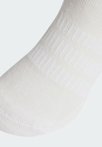 Biela ponožka s krátkym strihom z textúrovanej látky, so zúbkami v oblasti lemu. Dizajn je bez švov na prstoch, čo zabezpečuje hladké nosenie.