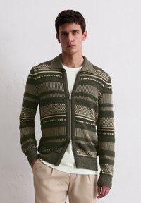 Sweter zapinany na zamek w ciemnozielonym kolorze, z beżowymi poziomymi paskami, teksturowanymi wzorami, kołnierzem i długimi rękawami. Lekki materiał.