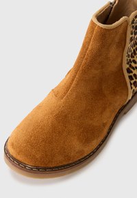 Wildleder-Ankle-Boots in Hellbraun mit glatter Textur. Mit einem Leopardenmuster auf der Seite und einem flexiblen elastischen Einsatz für ein einfaches Hineinschlüpfen.