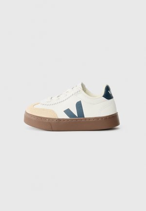 Baskets avec une tige en cuir blanc, des accents en suède beige clair, un logo bleu foncé et une semelle en caoutchouc marron. Design à lacets avec des détails texturés.