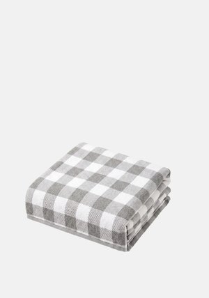 Serviette pliée à carreaux gris et blanc sur un fond clair uni.