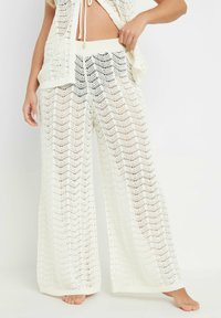 Pantalones de punto amplios de color blanco con un patrón de chevron y tejido texturizado. Acabados con una cinturilla elástica y puños anchos.