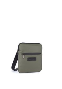 Borsa a tracolla in nylon verde oliva con tasca frontale con zip, dettaglio nero e patch con marchio. Texture liscia e forma rettangolare.