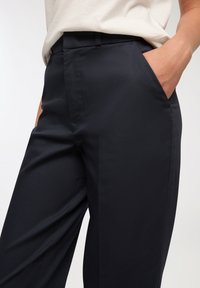 Granatowe spodnie wykonane z gładkiego materiału, z prostym krojem nogawek i bocznymi kieszeniami. Pas został zaprojektowany z myślą o eleganckim wyglądzie.