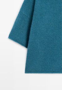 Indumento in lana verde acqua con una texture morbida. Presenta ampie maniche e un profilo pulito e moderno, che mette in risalto la ricchezza del tessuto.