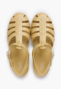 Yellow plastic sandals with open toe design, crisscross straps, an adjustable ankle strap, and a textured footbed.