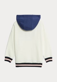 Sweat à capuche blanc avec capuche bleue, présentant des poignets et un ourlet côtelés en marine avec des rayures rouges et blanches. Tissu texturé.