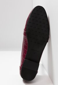 Semelle de mocassin bordeaux à motif crocodile avec talon et semelle en caoutchouc noir texturé, étiqueté "ANNA FIELD" taille 37.