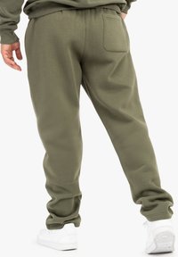 Olivenfarvede sweatpants med en afslappet pasform, elastisk talje og en enkelt baglomme. Blød tekstur og tætsiddende benåbninger.
