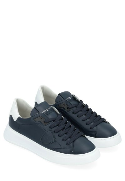 Baskets en cuir bleu marine avec des accents blancs, bout arrondi et design à lacets. Comprend une semelle en caoutchouc et un détail de logo sur le côté.