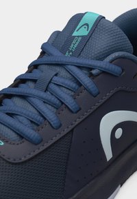 Námořnicky modrá teniska s texturovanou tkaninou, sladěnými tkaničkami, tyrkysovým logem na jazyku s nápisem „Sprint 4.0 Court JR“ a bílým logem na bočním panelu.