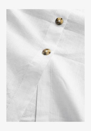 Chemise en lin blanche avec deux boutons marbrés marron et une texture subtile, dotée d'une patte de boutonnage sur le devant.
