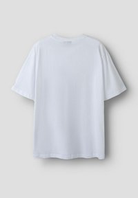 Camiseta blanca de manga corta mostrada desde la parte trasera sobre un fondo gris claro.