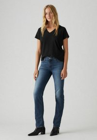 Black V-neck t-shirt paired with blue denim jeans and black ankle boots. The jeans have a straight-leg cut and subtle faded details.