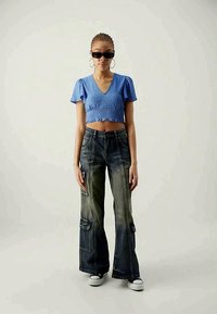 Zila īsa blūze ar teksturētu audumu un īsām piedurknēm, apvienota ar izgaismotām platām biksēm ar kabatām un baltām krekliņām.