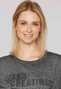 Czarny t-shirt w ciemnoszarym kolorze z okrągłym dekoltem, ozdobiony teksturą liter w czerni. Gładki materiał z lekkim połyskiem.