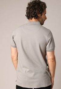 Grijze polo met een textuurstof, korte mouwen en een klassieke kraag. De achterkant heeft een naadafwerking en een getailleerde snit.
