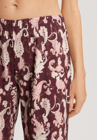 Paarse pyjamabroek met een bloemig paisleypatroon in lichtroze en wit. Heeft een elastische tailleband en zachte, textuurstof.