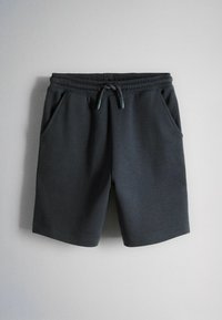 Shorts en coton gris foncé avec ceinture élastique, cordon de serrage et poches latérales, présentés sur un fond gris clair.