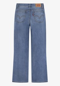 Vaqueros de pierna ancha azul claro, hechos de denim, con dos bolsillos traseros con detalles de costura y una etiqueta de cuero con la marca en la cinturilla.