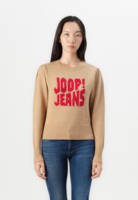 Beige gebreide trui met het rode "JOOP! JEANS" logo. Ribgebreide mouwen en zoom, ronde halslijn en een zachte textuur. Slim fit.