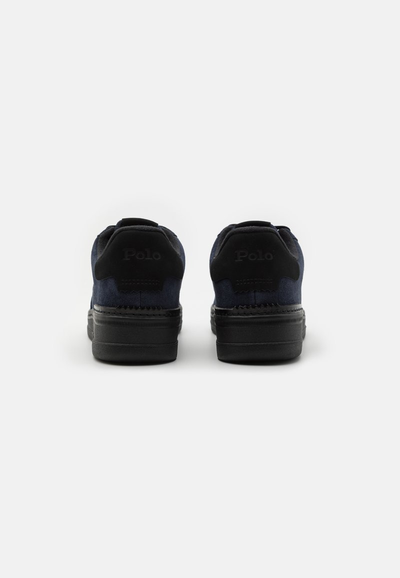Granatowe zamszowe sneakersy z czarną gumową podeszwą. Posiadają wytłoczone logo na pięcie oraz gładką teksturę bez widocznych wzorów.