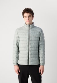 Light green, quilted puffer jacket with a high collar, front zipper, and ribbed cuffs. Features horizontal stitching and two side pockets.