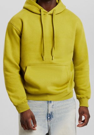 Klart gul hoodie med en framficka, dragsnören, ribbade ärmar och nederkant. Mjuk textur, avslappnad design. Bärs med ljusblå jeans.