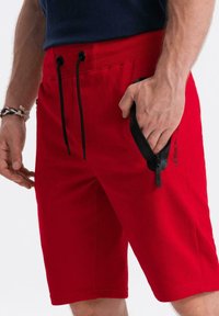 Rode shorts van een katoenmix, met een elastische tailleband met zwarte trekkoorden, een ritszak en een logo-opdruk op de zijkant.
