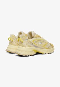 Helle gelbe Sportschuhe mit einem Obermaterial aus Mesh und Synthetik, runder Spitze, strukturiertem Profil und kleinen gelben Akzenten an der Ferse und den Schnürsenkeln.