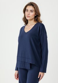 Top lungo a maniche lunghe blu navy con scollo a V, dal taglio morbido, caratterizzato da un design a strati all'orlo e un tessuto morbido e testurizzato.