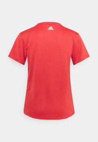 Červené tričko s krátkým rukávem, vyrobené z hladké tkaniny, má kulatý výstřih a malé bílé logo Adidas na horní části zad.