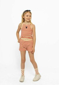 Ensemble débardeur à rayures et short en beige et rouge, avec un petit détail de cœur en marine ; associé à des chaussettes à motifs de cœurs et des baskets.