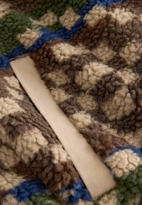 Textured fabric in brown, green, and blue patterns with a soft beige backing. Includes a fluffy, pile finish and contrasting color accents.